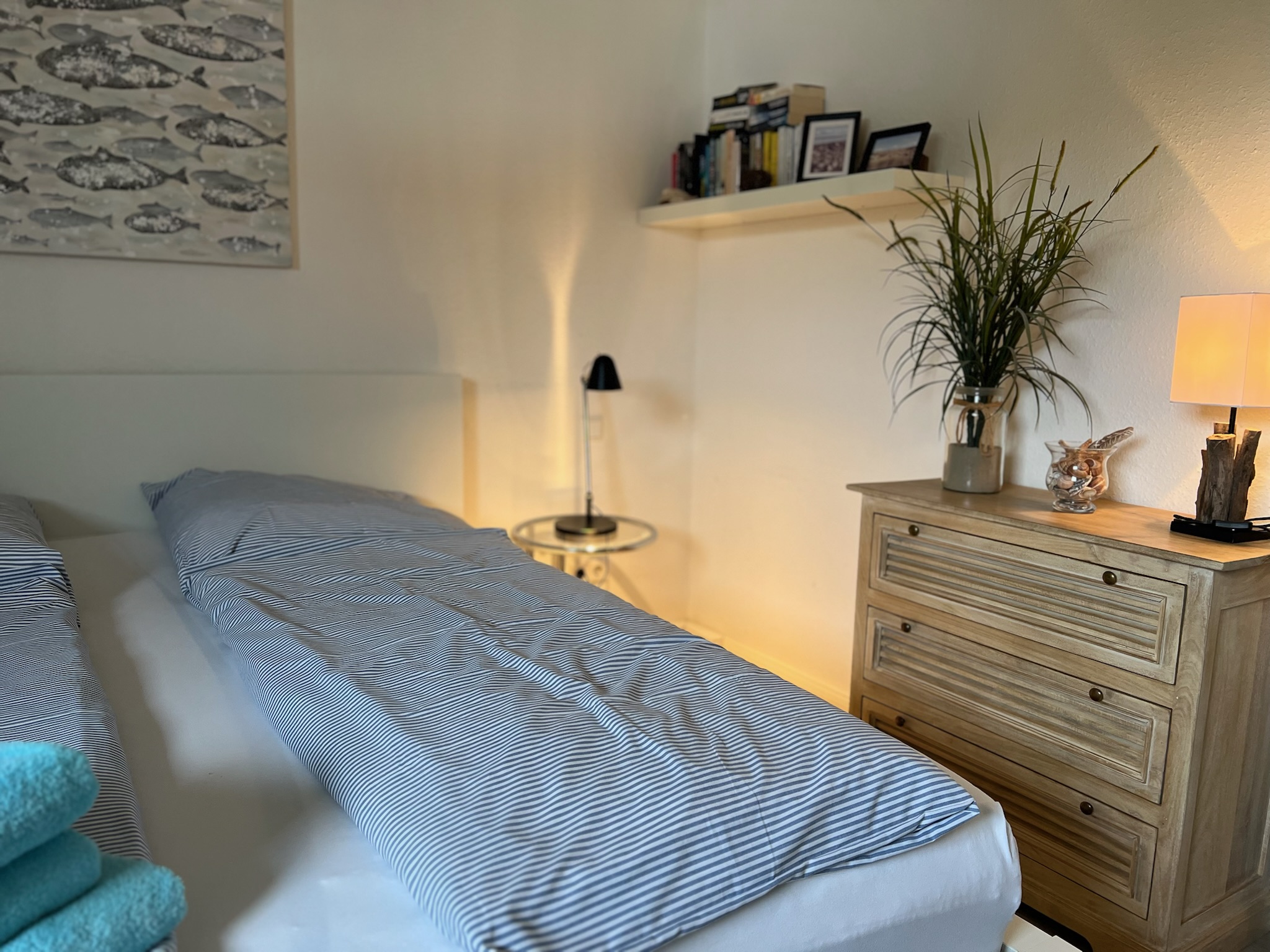 Separates Schlafzimmer mit gestreifter Bettwäsche und warmem Licht